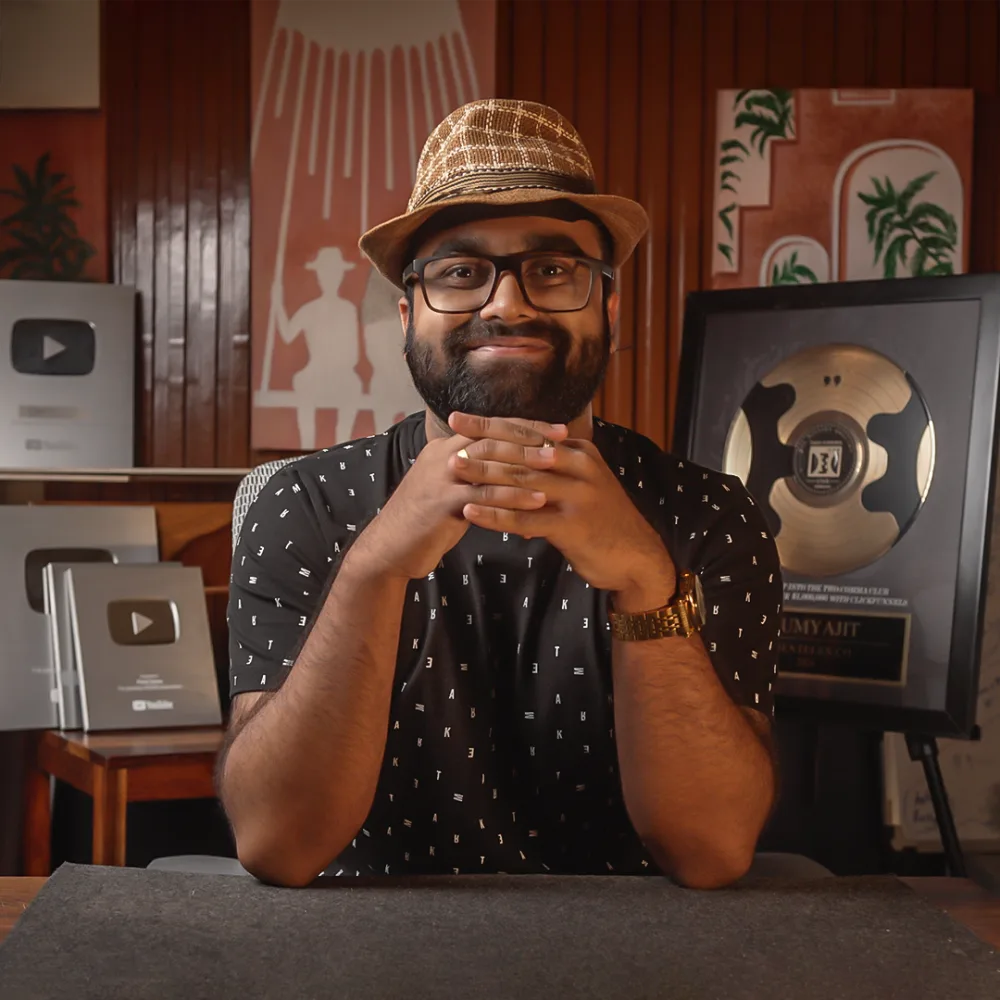 Samy, founder of Pixel Samy, at his desk with YouTube play button awards behind him